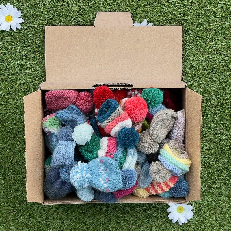 viele kleine gestrickte Hüte in einer Kiste